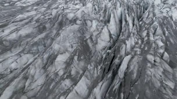 アイスランドのヴァトナヨークトル国立公園で雄大なスカフタフェル氷河を飛び越える モノクローム 空中傾斜下 — ストック動画