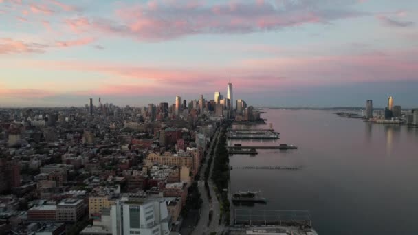 日の出に西側からニューヨーク州マンハッタンの空の眺め 遠くのフリーダムタワーの方へドローンカメラはドリーピンク 黄色の空 — ストック動画