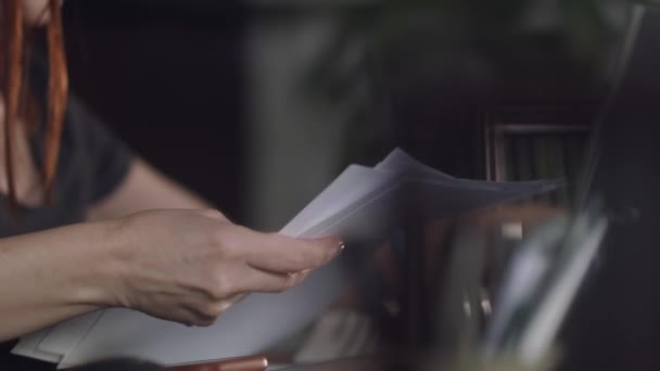 赤頭の女性は 自宅のオフィスでは 紙のシャッフル座っている 暗い雰囲気 — ストック動画