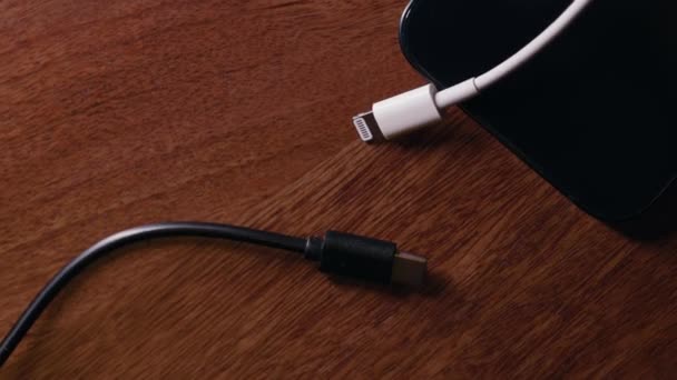 用智能手机在木制表面安装白色苹果闪电电缆和黑色Usb — 图库视频影像