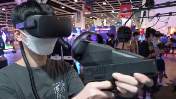 中国のゲーマーや観光客は 香港で開催された香港コンピュータ通信フェスティバルで仮想現実 マルチプレイヤーシューティングゲームをプレイします — ストック動画