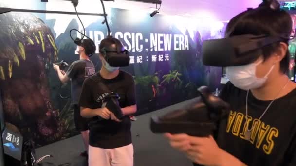 中国の若いゲーマーは 香港で開催されたコンピュータ通信フェスティバルでターゲットを読み込み ポイントし 撮影する際に 仮想現実 シューティングゲームをプレイします — ストック動画