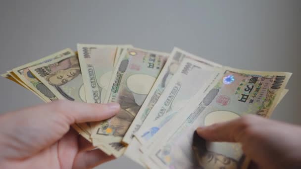 誰かの手のショットは いくつかの日本の通貨銀行券を保持し 白い環境でそれらを数える — ストック動画