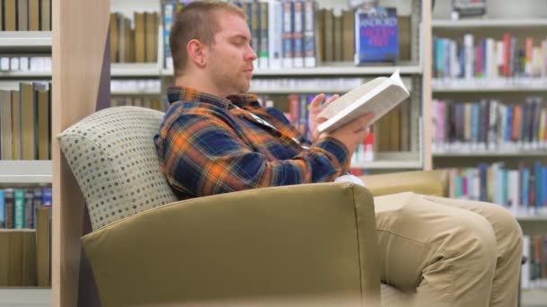 Чоловік Сидить Бібліотеці Читаючи Книгу Повільним Рухом — стокове відео
