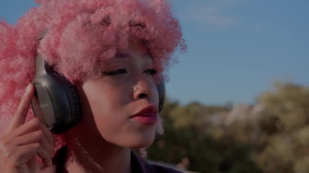 Черные Вьющиеся Розовые Волосы Девушки Слушающей Музыку Наушниках — стоковое видео