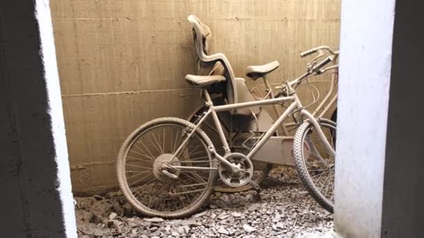 Två Övergivna Cyklar Med Plana Däck Kvar Lutande Sandvägg Grustäckt — Stockvideo