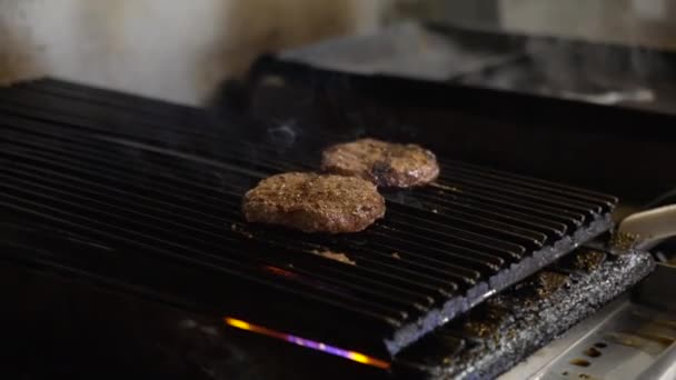 2つのハンバーガーのパテチャーとグリルの煙は 商業レストランのキッチンでオープン炎の上に格子 スローモーション4K — ストック動画
