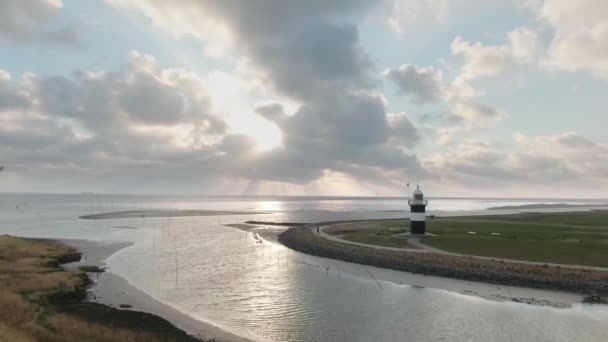 日没時にドイツの北海に隣接する灯台の空中ドローンショット — ストック動画