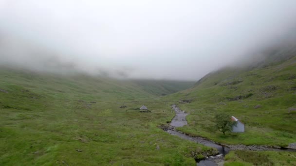 空中无人驾驶飞机的镜头在苏格兰的低低低的云彩中缓慢地向前飞行 飞向一条河流和Gameshope Bothy 一座山区避难所 苏格兰 — 图库视频影像