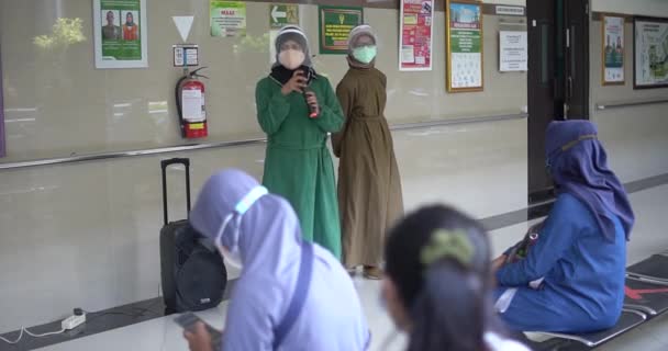 アジアの高齢者のグループは 病院のパビリオンに列に座って 治療セッション中に2人の看護師に耳を傾けます — ストック動画