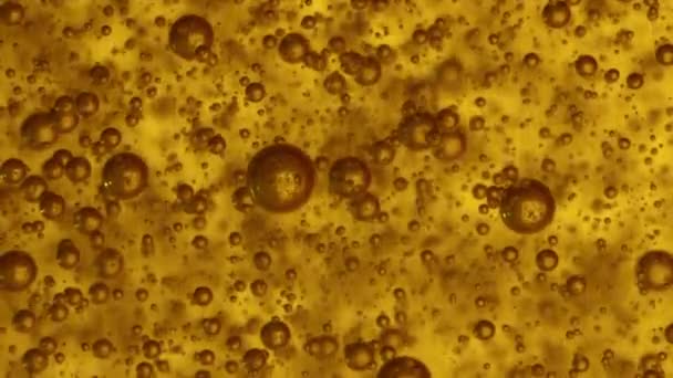 黄色の液体の中でスロモ マクロ気体の半透明の褐色の泡が立ち上がり — ストック動画