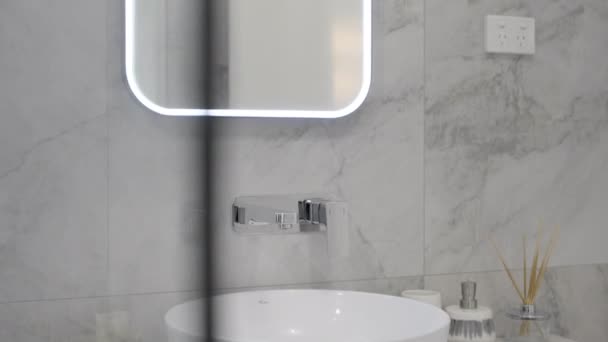 现代浴室与黑暗的瓷砖和白色的固定装置在一个现代住宅 浴室的虚荣 华丽的灰色瓷砖 点亮镜子 玻璃淋浴器 — 图库视频影像