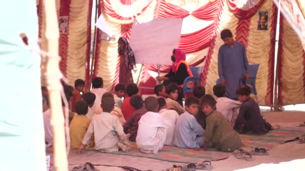 パキスタンの地面に座っている小さな男の子と女の子を教えている小さな教室のビデオ — ストック動画