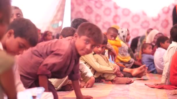 彼らの前に本がある学校のマットに座ってパキスタンのカメラを見ている多くの男の子 — ストック動画