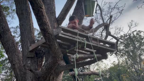 Yaratıcı Bir Çocuk Ağaç Eve Kova Bağlamak Için Kullanır — Stok video