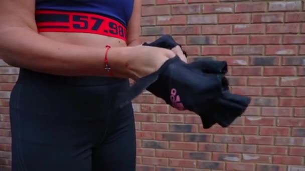 近距离观察年轻女运动员将双手插在有品牌的运动锻炼专用手套上 — 图库视频影像