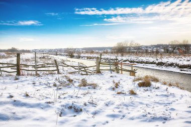 Gün batımında nehir kıyısında kış manzarası. Kar ve nehirle kaplı güzel kış manzarası