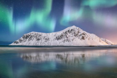 Geceleri Skagsanden sahilinde kuzey ışıklarıyla muhteşem bir kış manzarası. Popüler turizm merkezi. Konum: Flakstadoya Adası, Lofoten; Norveç, Avrupa