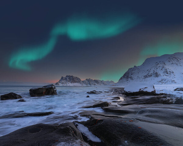Amazing winter scenery on Uttakleiv beach at night with Northern lights. Popular tourist destination. Location: Vestvagoy island, Lofoten; Norway, Europe