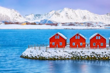 Gorgeous scenery wit traditional red wooden houses on the shore of Offersoystraumen fjord. Popular travel destination on Lofotens. Location: Vestvagoy island, Lofoten; Norway, Europe