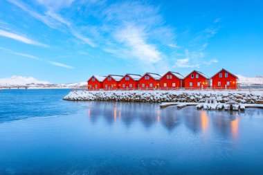Gorgeous scenery wit traditional red wooden houses on the shore of Offersoystraumen fjord. Popular travel destination on Lofotens. Location: Vestvagoy island, Lofoten; Norway, Europe
