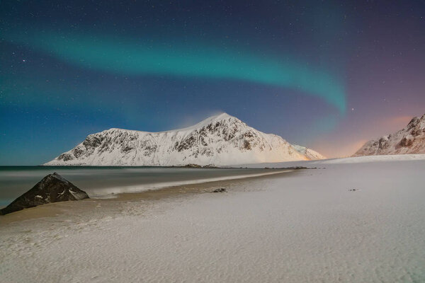 Fabulous winter scenery on Skagsanden beach at night with Northern lights. Popular tourist destination. Location: Flakstadoya island, Lofoten; Norway, Europe