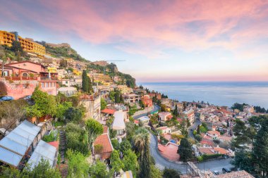 Stunning Aquamarine blue waters of sea and fantastic cityscape of Taormina during sunset. Giardini-Naxos bay, Ionian sea coast, Taormina, Sicily, Italy.