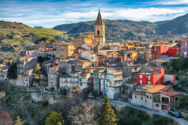 Amazing Panorama of the belltower and the village in the valley at early sunrise. Mountain village Novara di Sicilia, Sicily, Italy