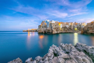 Fantastic night scene at Cala Paura gulf with Bastione di Santo Stefano in village on the rocks Polignano a Mare, Apulia, Italy, province of Bari.