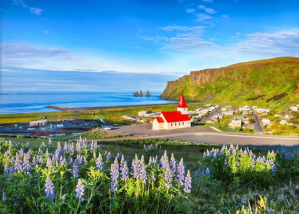 Vikurkirkjaキリスト教の教会の息をのむような景色は ラインの花を咲かせます 最も人気のある観光地 ヨーロッパ アイスランドのミュルダル バレーのヴィック村 ロイヤリティフリーのストック画像