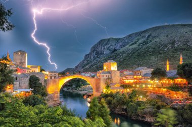 Akşamları Mostar Köprüsü, evler ve minarelerle Mostar 'ın görkemli akşam manzarası. Konum: Mostar, Old Town, Bosna-Hersek, Avrupa