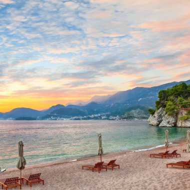 Captivating sunset at beach with chaise lounges and umbrellas in Sveti Stefan near Budva. Location: Budva riviera, Montenegro, Adriatic sea, Europe clipart