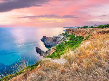 Cape Fiolent 'te büyüleyici bir günbatımı çalılar ve kayalar ön planda. Konum: Kırım, Pelerin Fiolent
