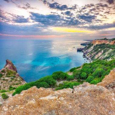 Cape Fiolent 'te büyüleyici bir günbatımı çalılar ve kayalar ön planda. Konum: Kırım, Pelerin Fiolent