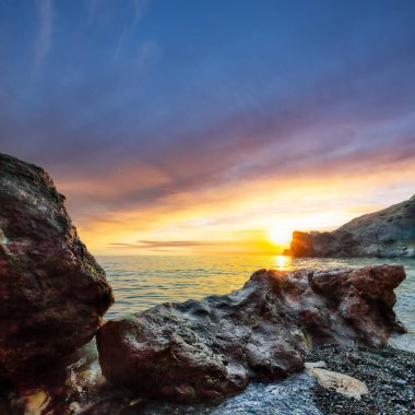 Gün batımında inanılmaz deniz manzarası. Uzun vadede güzel bir deniz manzarası. Önplanda taşlar