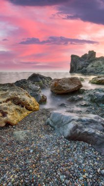 Gün batımında inanılmaz deniz manzarası. Uzun vadede güzel bir deniz manzarası. Önplanda taşlar