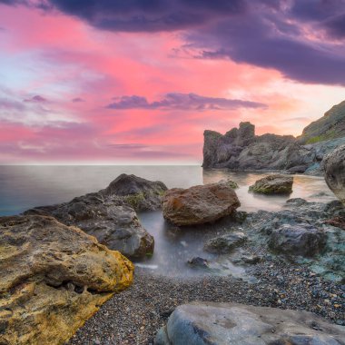 Gün batımında inanılmaz deniz manzarası. Uzun vadede güzel bir deniz manzarası. Önplanda taşlar