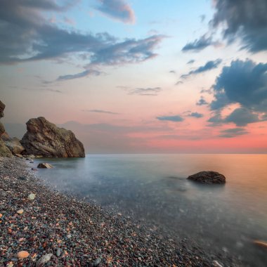 Gün batımında inanılmaz deniz manzarası. Uzun vadede güzel bir deniz manzarası. Önplanda taşlar