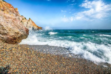 Deniz dalgalarının kıyıya çarpması ve deniz çakıl taşlarının üzerinde akışının inanılmaz görüntüsü. Kaya sahili.