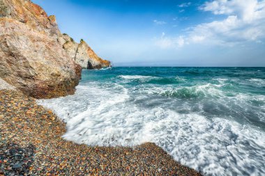 Deniz dalgalarının kıyıya çarpması ve deniz çakıl taşlarının üzerinde akışının inanılmaz görüntüsü. Kaya sahili.