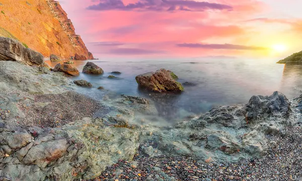 Gün batımında inanılmaz deniz manzarası. Uzun vadede güzel bir deniz manzarası. Önplanda taşlar