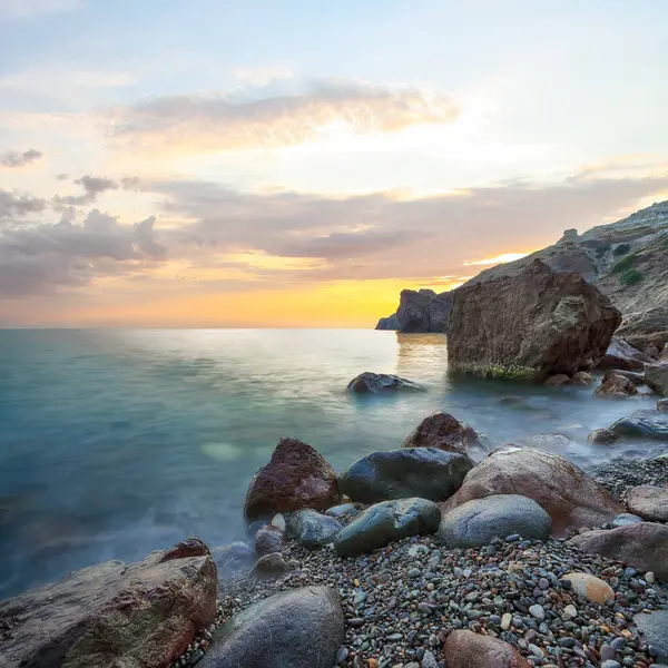 Gün batımında inanılmaz deniz manzarası. Uzun vadede güzel bir deniz manzarası. Önplanda taşlar