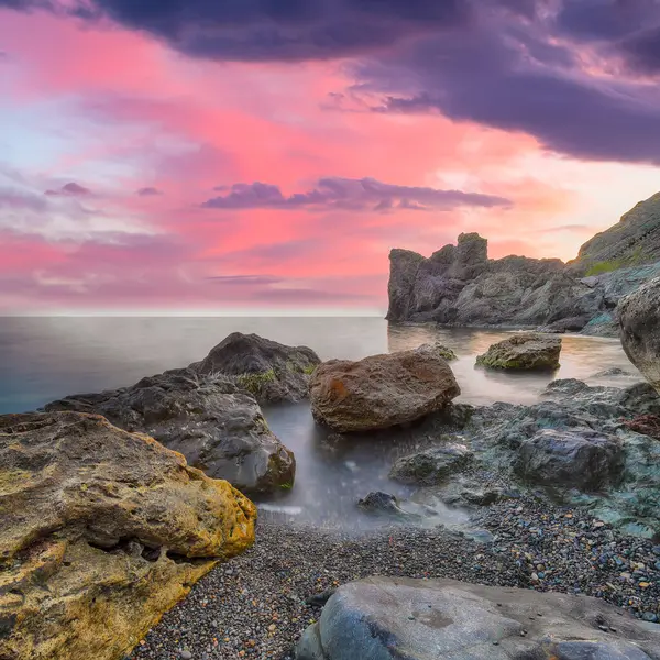 Gün batımında inanılmaz deniz manzarası. Uzun vadede güzel bir deniz manzarası. Önplanda taşlar