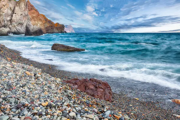 Deniz dalgalarının kıyıya çarpması ve deniz çakıl taşlarının üzerinde akışının inanılmaz görüntüsü. Kaya sahili.