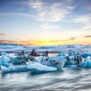 Gün batımında Jokulsarlon Buzul Gölü 'nde yüzen buzdağlarıyla muhteşem bir manzara. Konum: Jokulsarlon Buzul Gölü, Vatnajokull Ulusal Parkı, Güney İzlanda, Avrupa