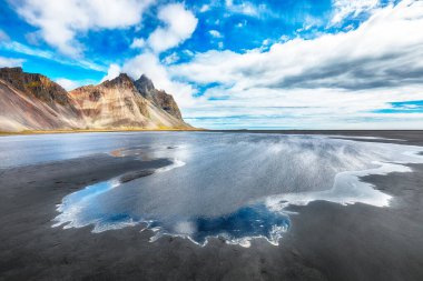 İnanılmaz güneşli bir gün ve İzlanda 'daki Stokksnes Pelerini' ndeki Vestrahorn Dağı 'nın muhteşem yansıması. Konum: Stoksnes Pelerini, Vestrahorn (Batman Dağı), İzlanda, Avrupa.