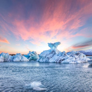 Gün batımında Jokulsarlon buzul gölünde yüzen buzdağlarıyla etkileyici bir manzara. Konum: Jokulsarlon Buzul Gölü, Vatnajokull Ulusal Parkı, Güney İzlanda, Avrupa