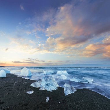 Gün batımında Jokulsarlon lagünündeki ünlü Diamond Sahili 'nde buzdağının dokunulabilir parçaları parlıyor. Konum: Jokulsarlon Lagünü, Diamond Sahili, Vatnajokull Ulusal Parkı, İzlanda, Avrupa