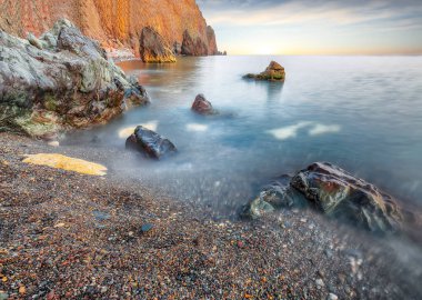 Gün batımında inanılmaz deniz manzarası. Uzun vadede güzel bir deniz manzarası. Önplanda taşlar