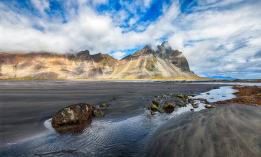 İnanılmaz güneşli bir gün ve İzlanda 'daki Stoksnes Burnu' nda dramatik bir kara kum plajı. Konum: Stoksnes Pelerini, Vestrahorn (Batman Dağı), İzlanda, Avrupa.